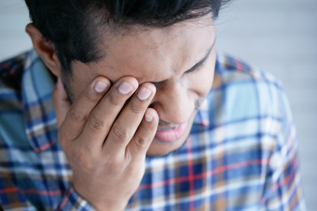 A close-up of a patient rubbing his eye and temple in pain. This is a common symptom of cataracts, and may indicate it is time to consider cataract surgery near Short Pump.